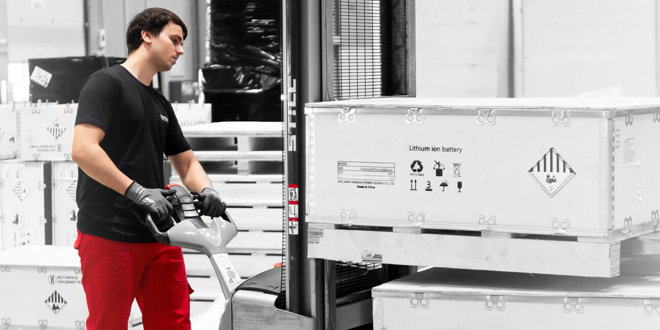 Mitarbeiter verlädt Transportkisten für Lithium-Ionen-Batterien mit einem Hubwagen.